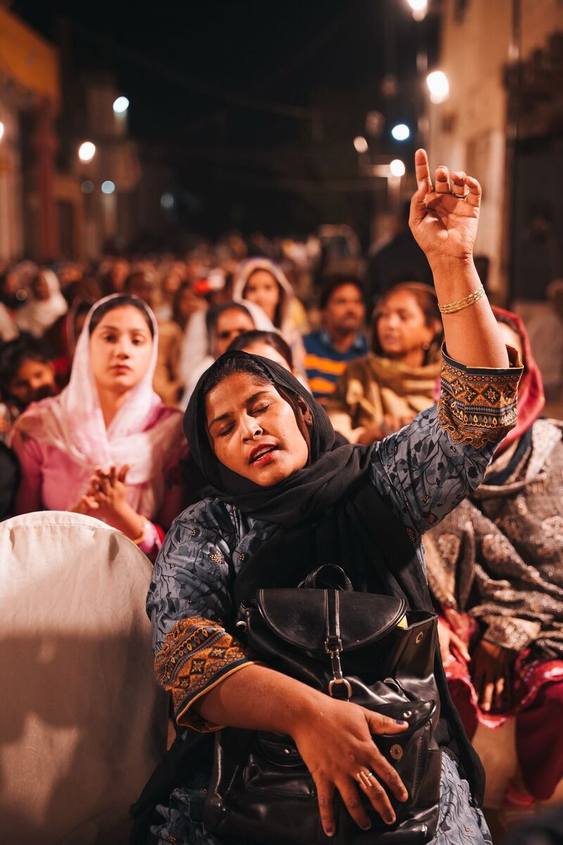 A woman worshiping with her hand raised in the street